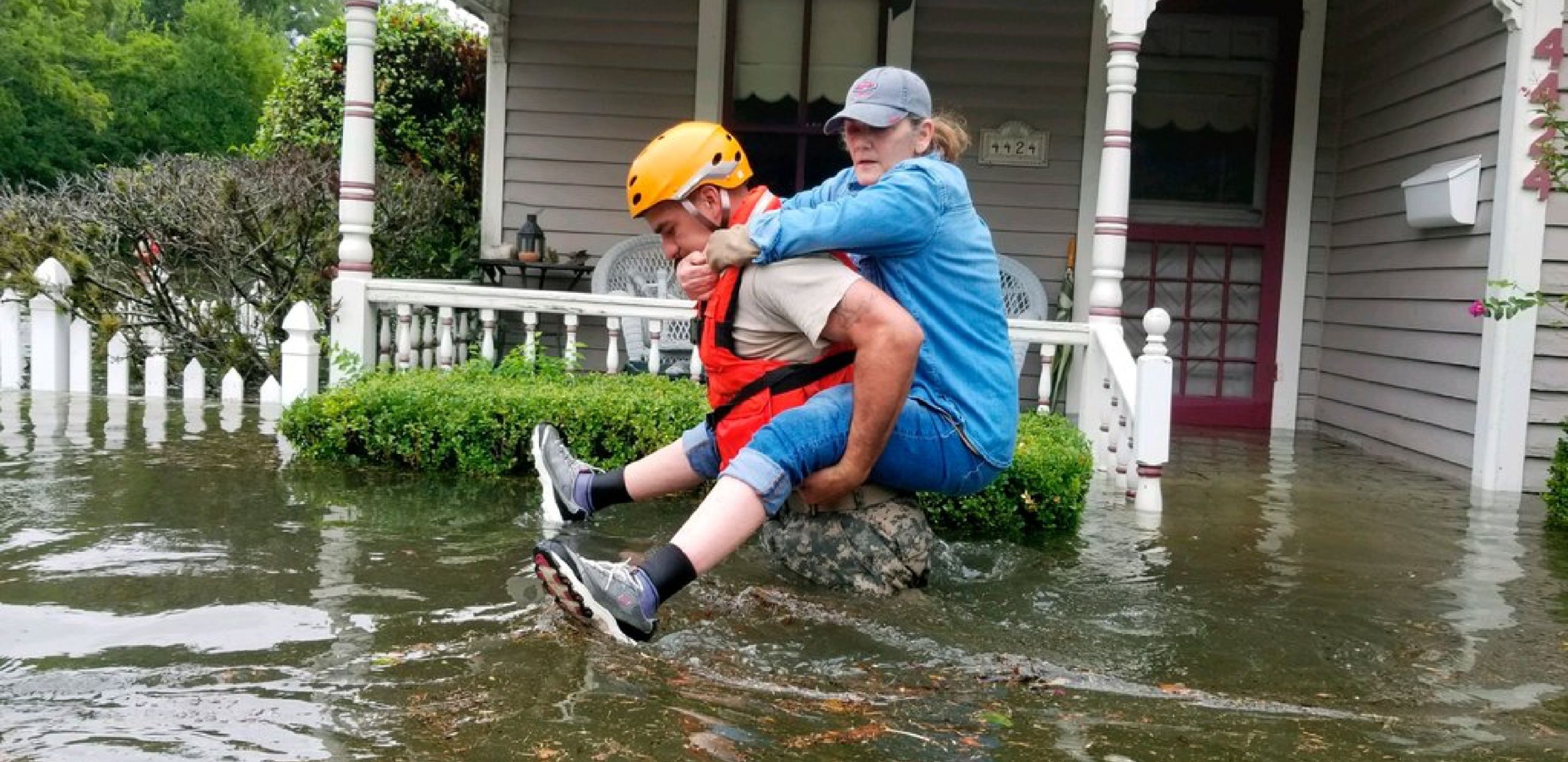 A man carries a woman on his back through flood waters in Texas