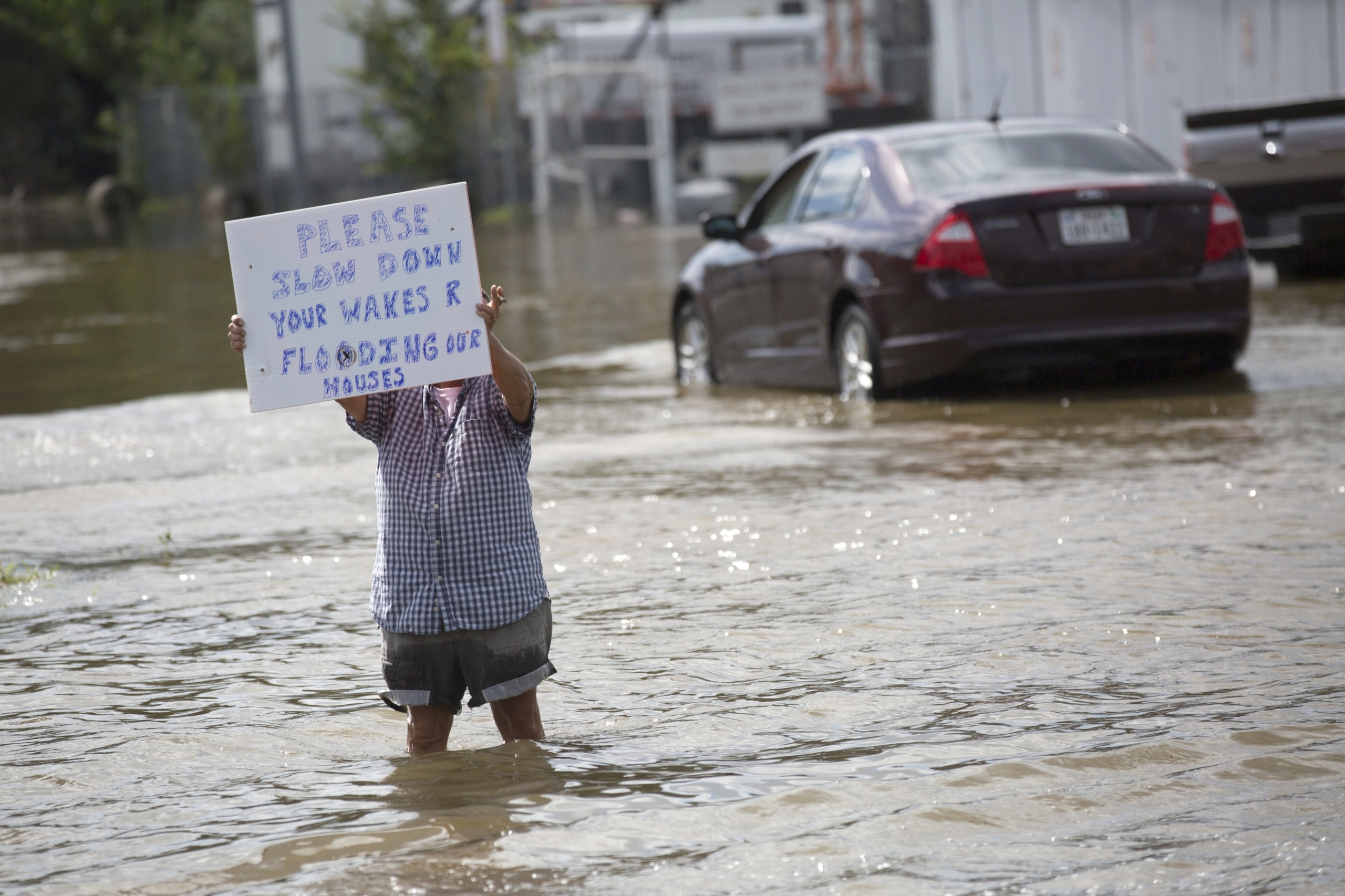 man in flood waters holding sign
