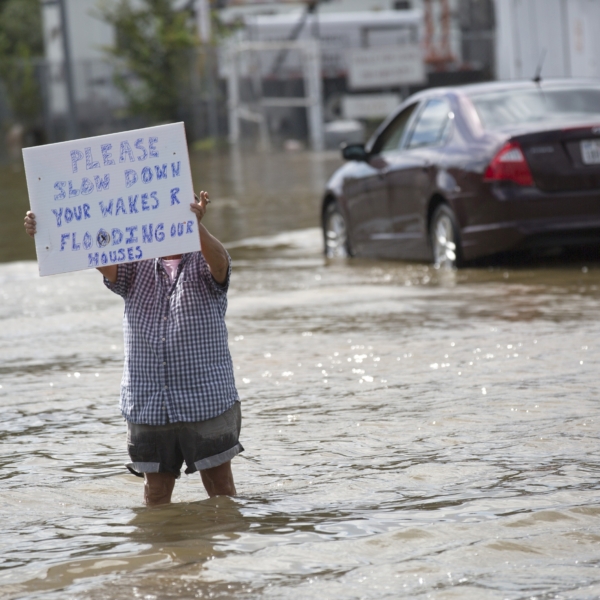 man in flood waters holding sign