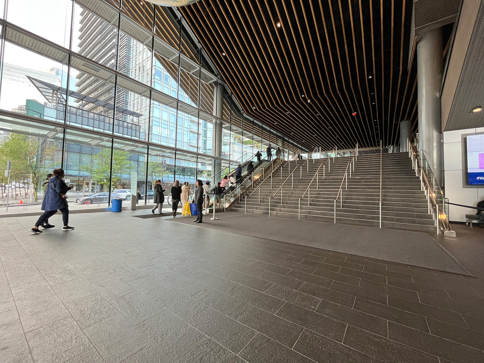 View of the stairs and escalator at the main entrance foyer, leading to the conference hall level. Escalators are to the left of the stairs.