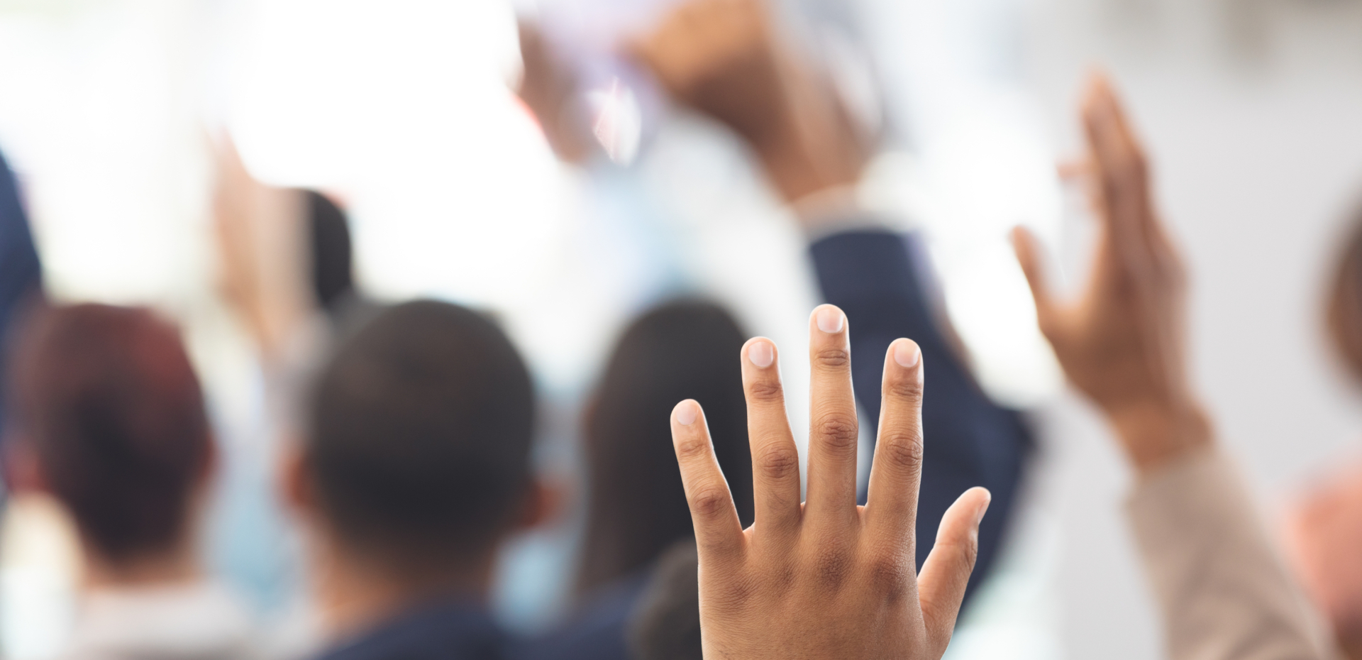 Close-up of multi-ethnic hands being raised in a business seminar in office building.