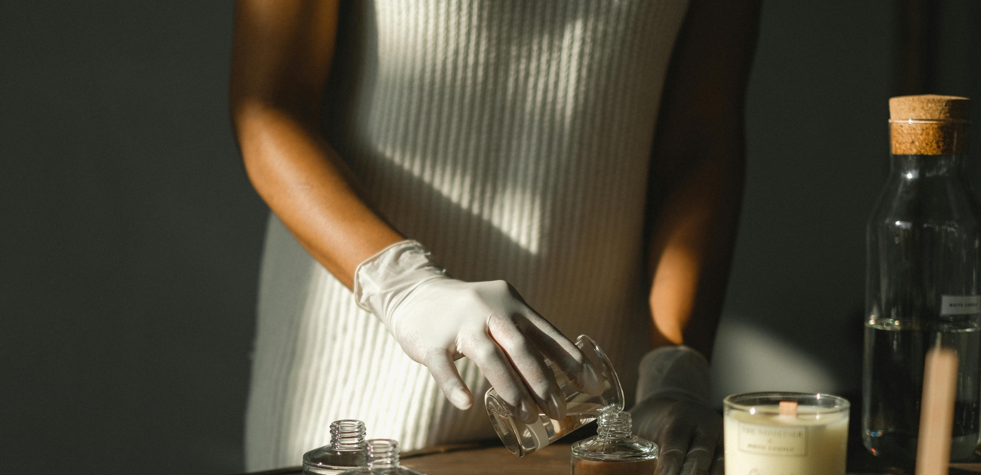 Woman filling a glass jar with candle wax