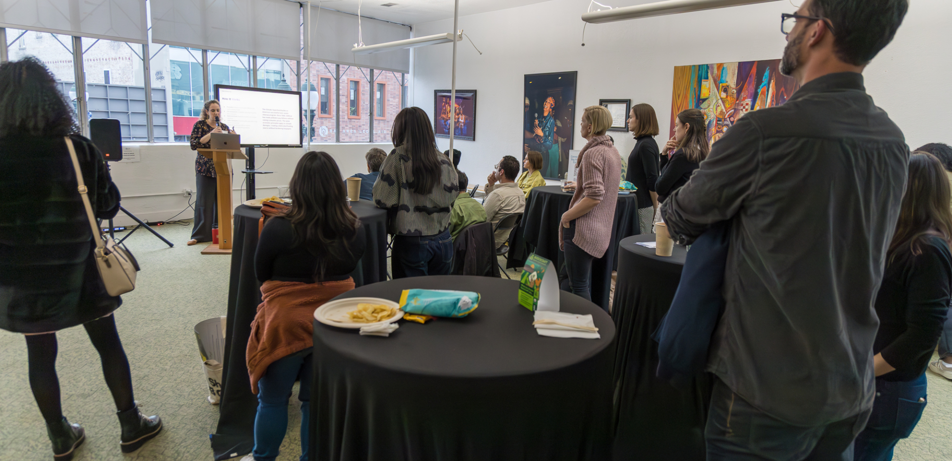 A woman speaks to a small crowd of B Corp leaders in a meeting room.